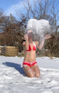Frau beim Schneebaden wirft Schnee nach oben