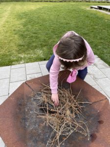 Kind holt ein Ei aus der Feuerschale