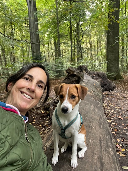 Frau mit Hund auf Baumstamm