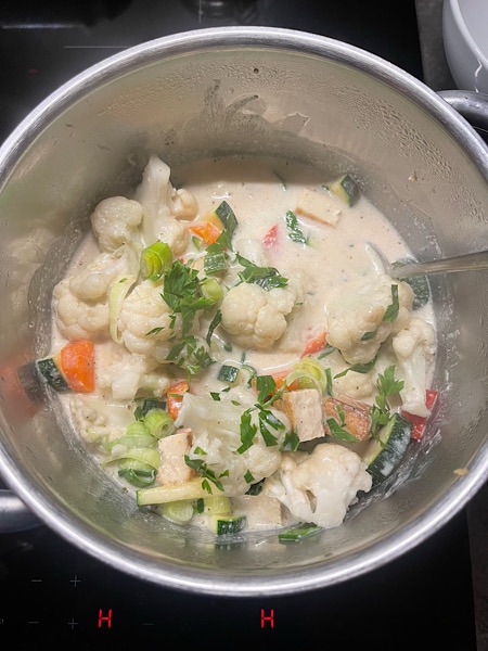 Kokossuppe mit viel Gemüse in einem Edelstahltopf