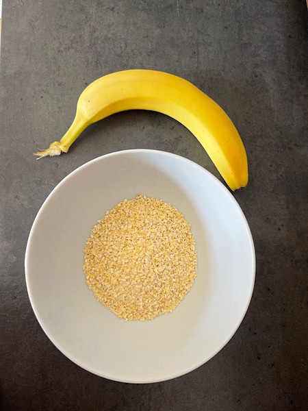 Banane und Hirseflocken in weißer Porzellanschale