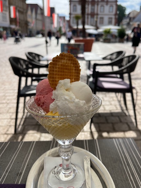 Eisbecher mit Mango-, Himbeer- und Zitroneneis in einer Glasschale.
