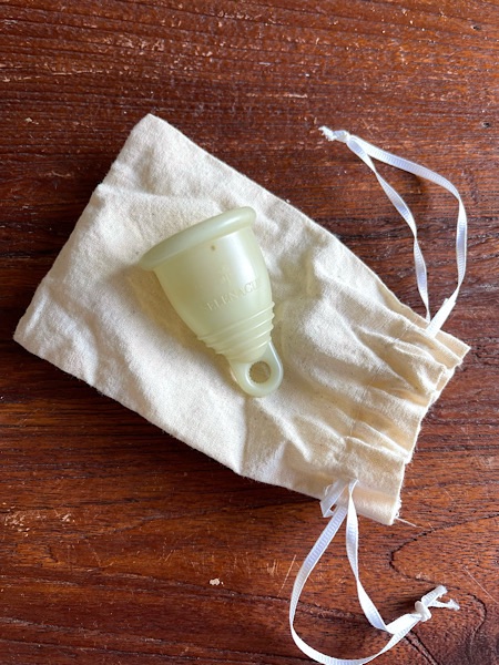 cremefarbene Menstruationstasse mit Aufbewahrungsbeutel