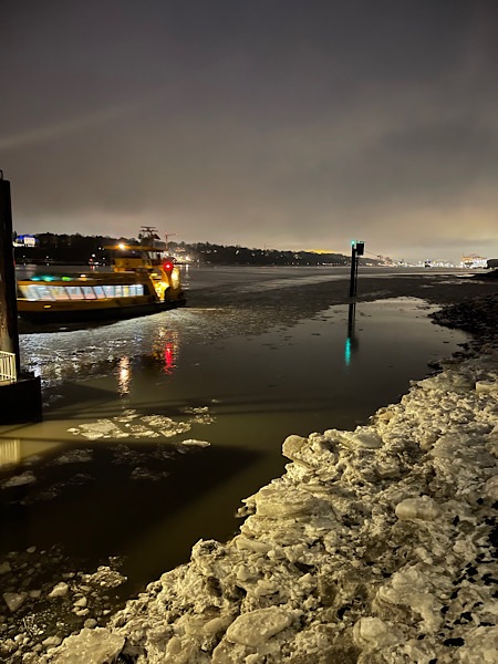 Elbe vom Fähranleger Rüschpark am Abend im Winter mit Eisscholllen und heranfahrender Fähre.